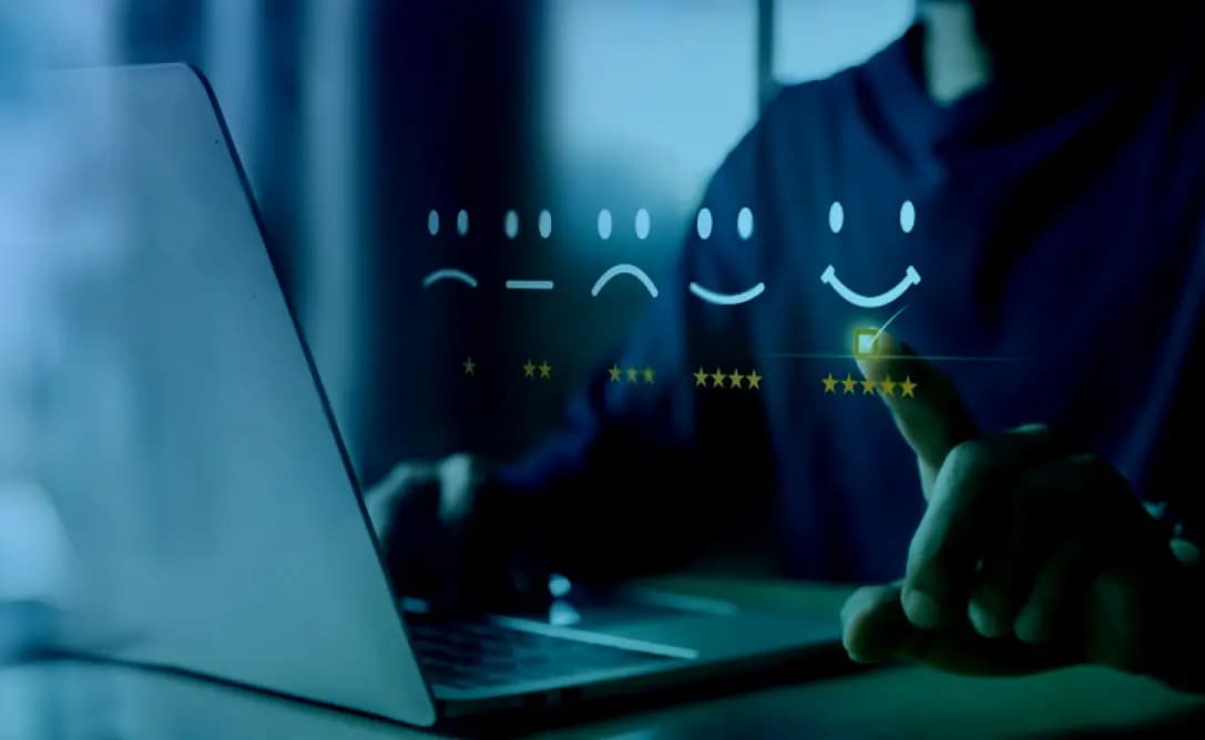 Person using a laptop with a row of smiley face icons indicating different levels of satisfaction, highlighting a positive customer feedback experience.